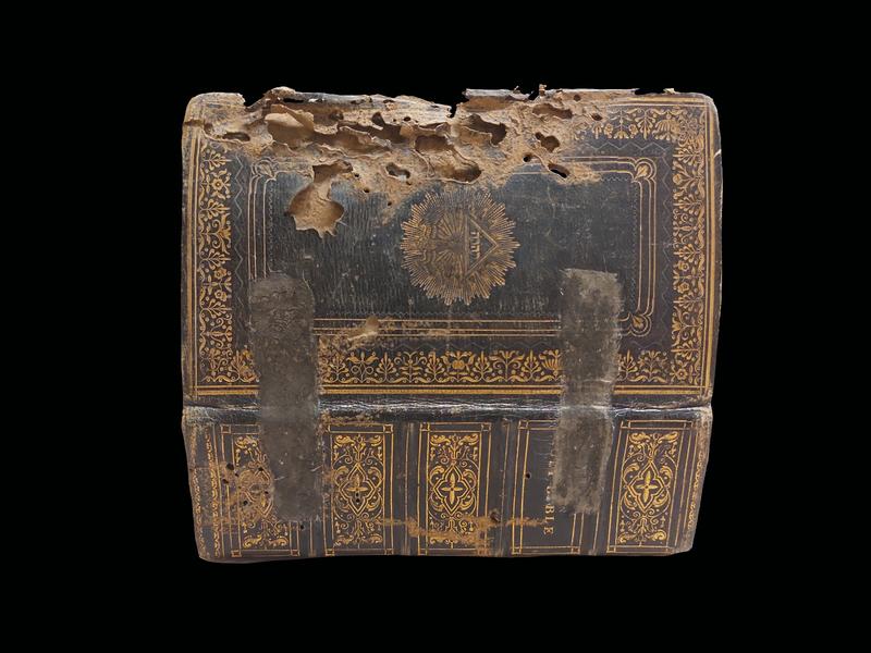 A cover of a bible with holes and grazing lines which has been eaten by bookworms
