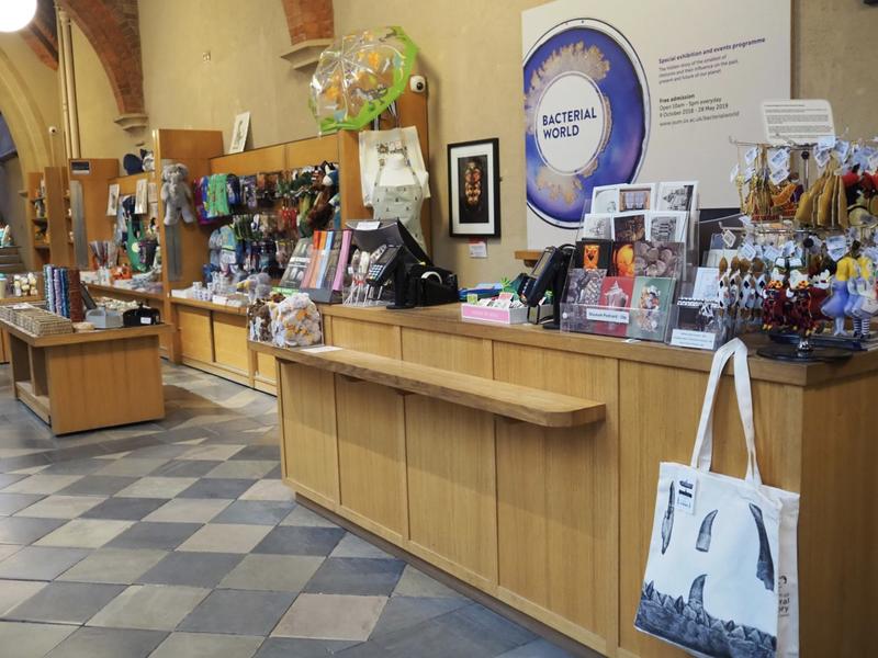 The Museum shop as seen from the Welcome Desk, with a counter in front of the camera man and the rest of the shop extending to the left.