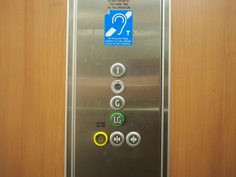 The buttons in the lift which are, in descending order, First Floor, a blank button, Ground Floor, Lower Ground Floor, & a horizontal row of three buttons at the bottom: alarm button on the left, a close button in the middle, and an open button on right