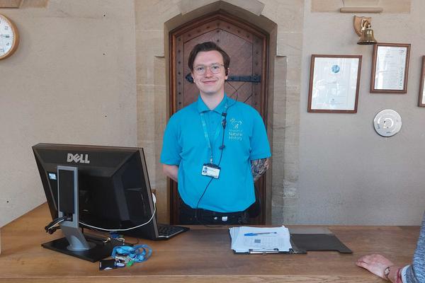 A Visitor Services Assistant wearing a light blue polo shirt with an embroidered logo