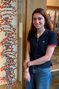 A STEM placement student at the Museum beside a model of DNA